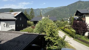 Un village rural avec des maisons traditionnelles, une route sinueuse et des montagnes en arrière-plan.
