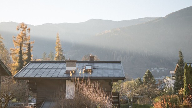 Une maison avec un toit en pente, des panneaux solaires et un petit jardin.