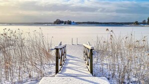 Un sentier enneigé qui mène à un lac gelé, sous un ciel dégagé.