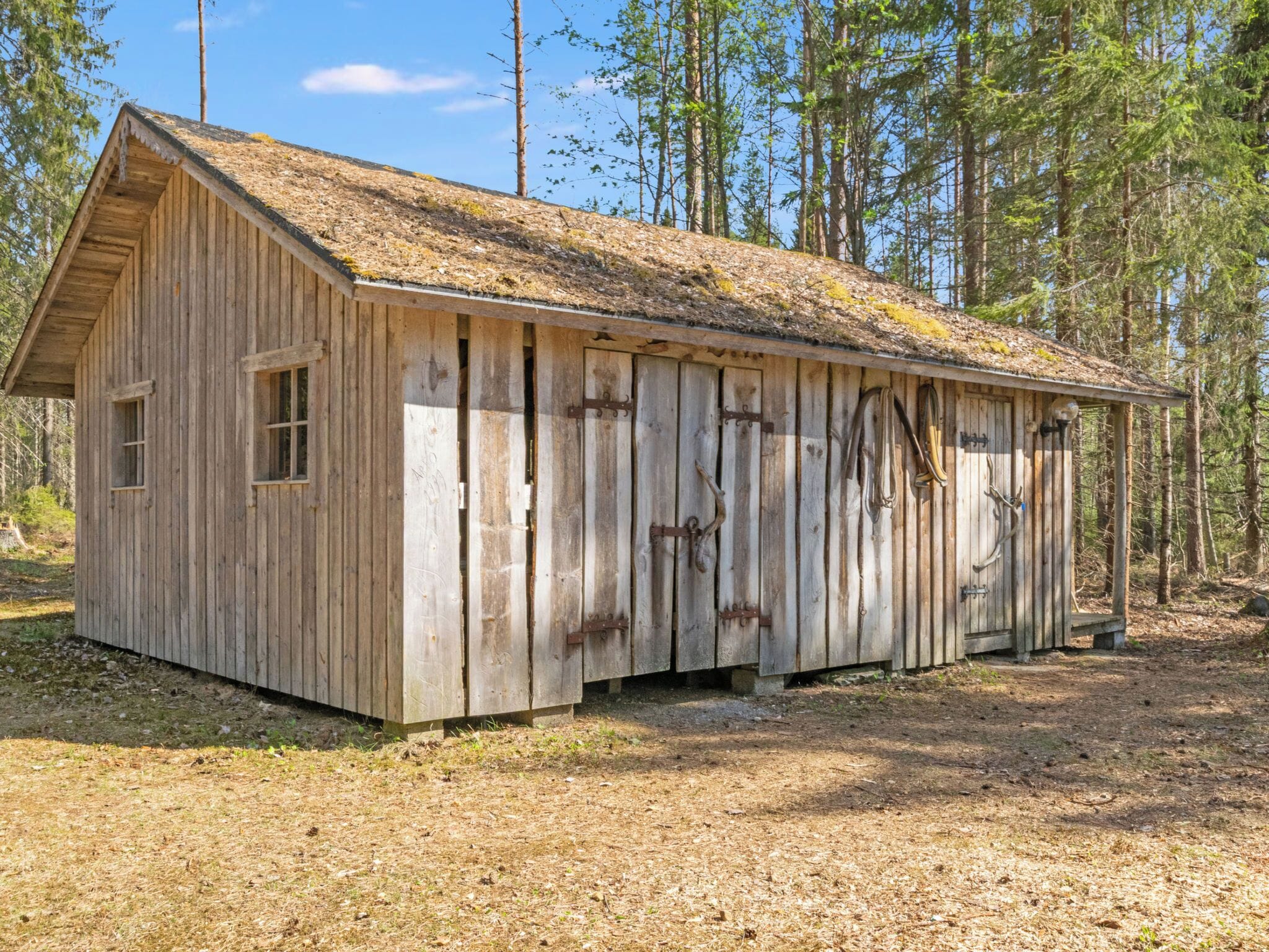 A rustic wooden cabin with a sloped roof, large windows, and a door.