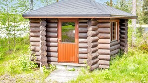 A small log cabin with a wooden door and window, surrounded by trees and grass. - Paloniemi by Interhome (Savitaipale)