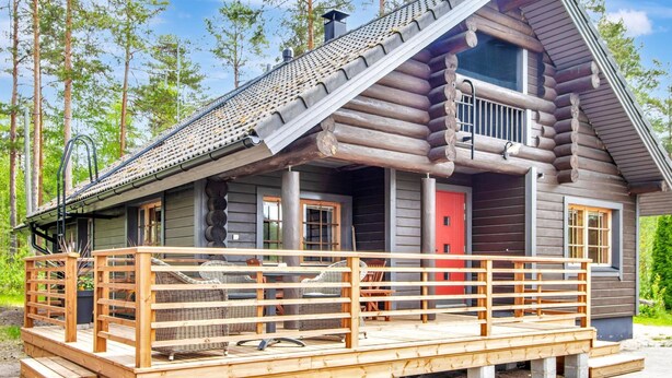 A log cabin with a wooden deck, a red door, and a balcony. - Paloniemi by Interhome (Savitaipale)