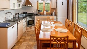Una cocina compacta con una mesa de madera dispuesta para comer, un horno empotrado y un refrigerador.