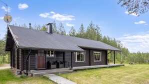 A log cabin with a porch, a chimney, and a satellite dish.