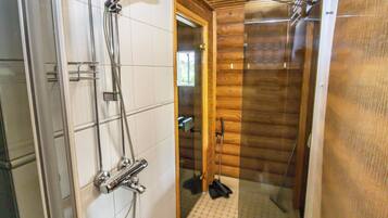 A shower area with a glass door, wooden walls, and a tiled floor.