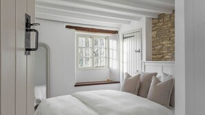 Une chambre à coucher avec un lit, une fenêtre, un mur en pierre et une porte.