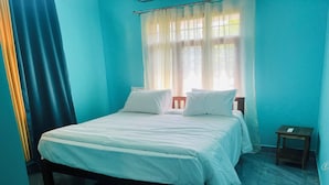 Een slaapkamer met een bed, nachtkastje en een raam met gordijnen.