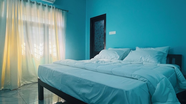 Een slaapkamer met een bed, gordijnen en een wandairconditioner.