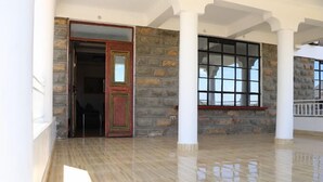 A spacious room with a stone wall, a wooden door, and a large window. - Kimberly Guest House Naivasha (Naivasha)