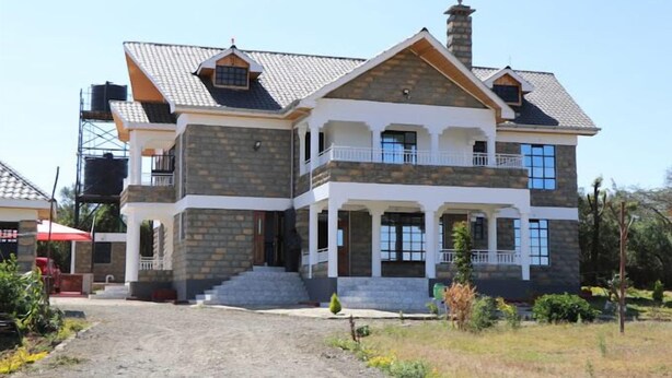 A two-story house with a stone facade, a balcony, and a chimney. - Kimberly Guest House Naivasha (Naivasha)