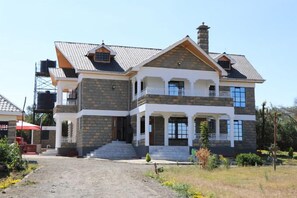 Une maison à deux étages avec une façade en pierre, un balcon et une cheminée.
