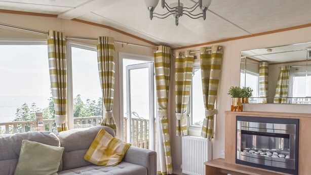 Ett vardagsrum med en soffa, en öppen spis och utsikt över naturen.