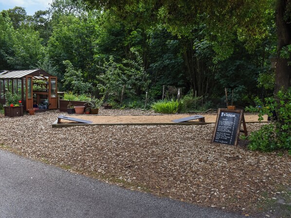 A garden with a wooden structure, possibly a greenhouse, surrounded by dense foliage.