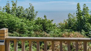 A wooden deck overlooking a lush green landscape with a view of the sea. - Seaview Two - UK50166 (Corton)