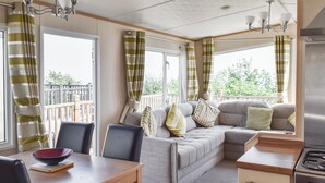 A compact living space with a sofa, dining table, chairs, and a kitchenette. - Seaview Two - UK50166 (Corton)