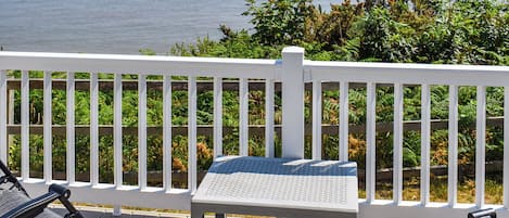 En træterrasse med hvid gelænder, et lille bord og en stol.