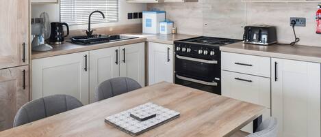 A modern kitchen with white cabinets, a wooden dining table, and a built-in oven.