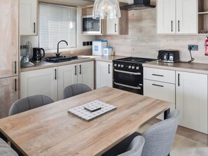 Una cocina moderna con armarios blancos, una mesa de comedor de madera y un horno empotrado.