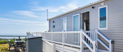 Ein eingeschossiges Mobilheim mit Veranda und kleiner Terrasse.