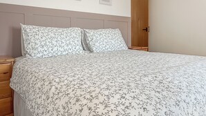 Ein Schlafzimmer mit einem Bett, zwei Nachttischen, einer Holztür und drei gerahmten Bildern an der Wand.
