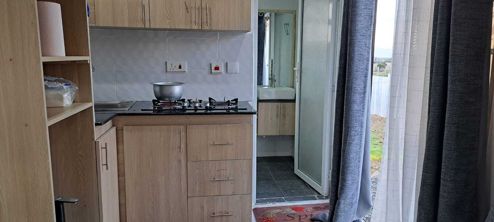 Eine kleine Küche mit Gasherd, einem Kochtopf und Holzschränken.