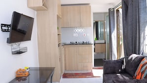 Une cuisine compacte avec des meubles en bois, une cuisinière encastrée et un téléviseur fixé au mur.