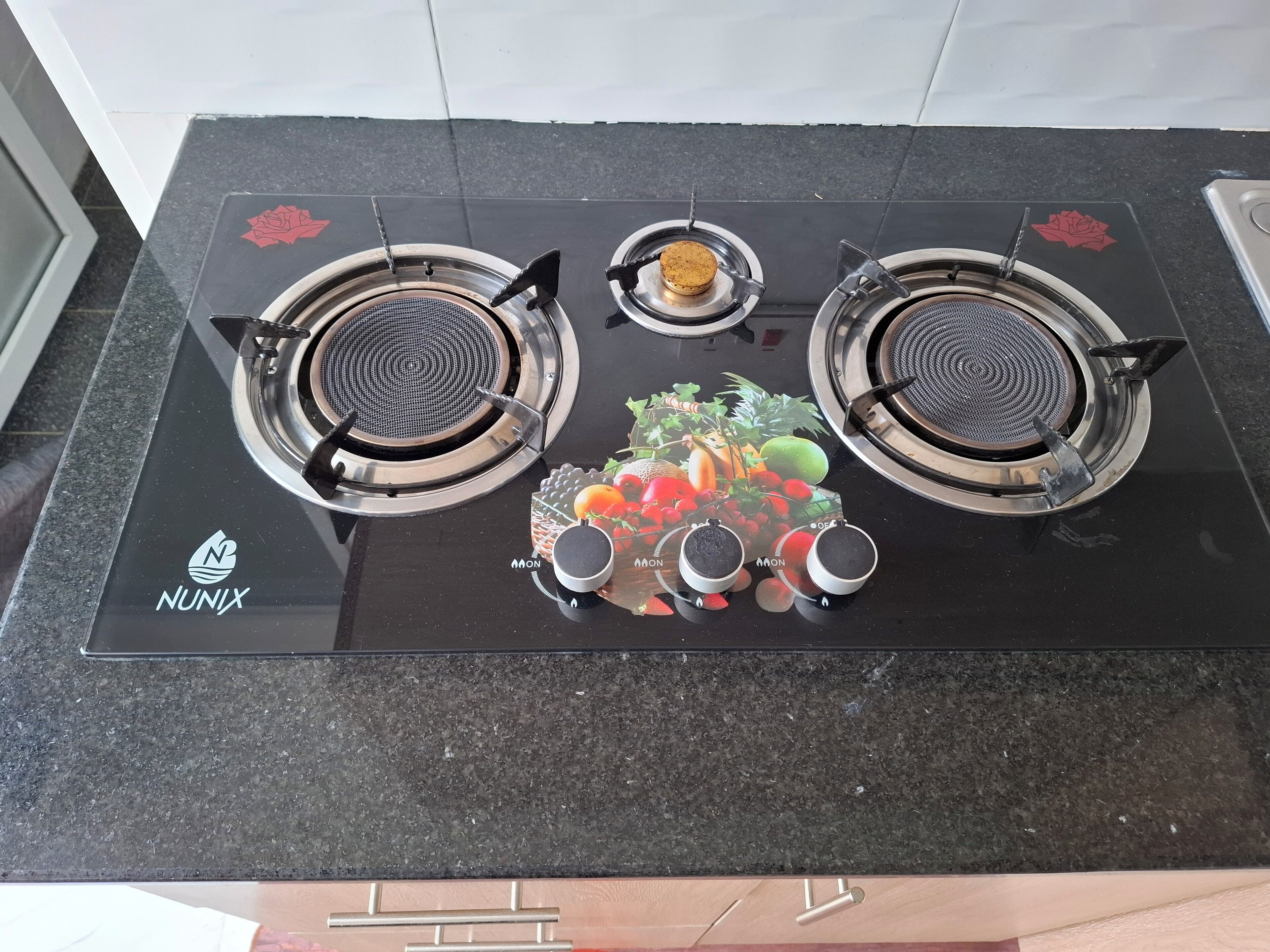 Una cocina con encimera negra, dos hornillas y el logotipo de NUNIX.
