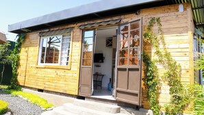 Une maison en bois avec une grande porte ouverte, une petite table à l’intérieur et un téléviseur fixé au mur.