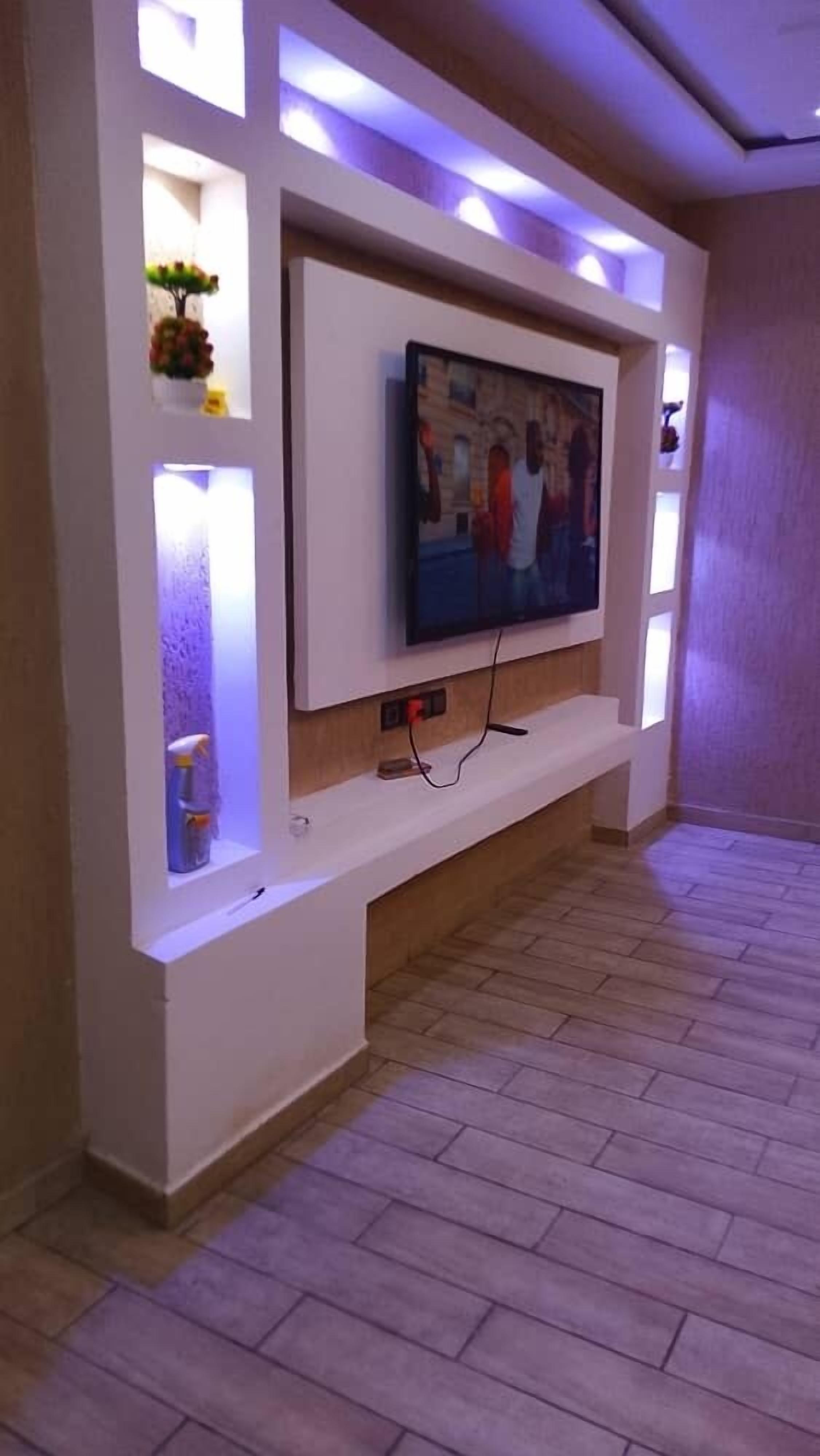 A modern living room with a flat-screen TV mounted on a white entertainment unit.