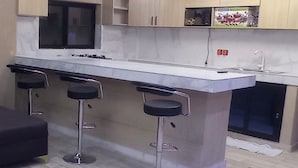 Una cocina moderna con una isla central, tres taburetes de bar y un sofá negro.
