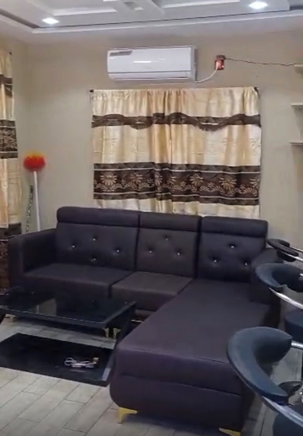 Una sala de estar con un sofá modular, una mesa de centro, un mueble para televisión y un equipo de aire acondicionado.