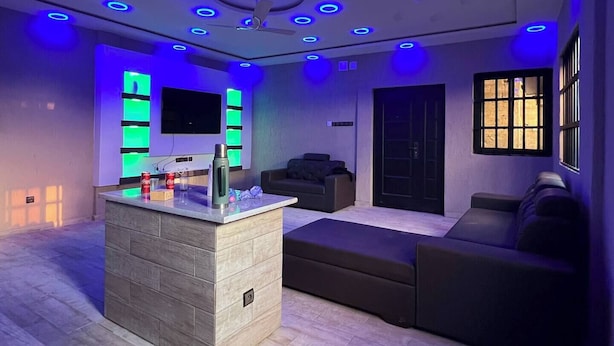 Una sala de estar moderna con una isla central, un sofá y un televisor montado en la pared.