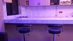 Una cocina moderna con dos taburetes de bar, un banco negro y un microondas.