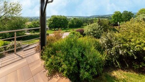 Un balcón con vistas a un jardín exuberante y colinas lejanas.