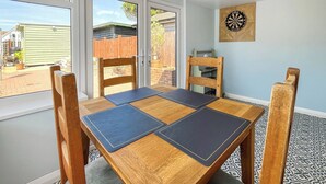 A dining area with a wooden table, four chairs, and a dartboard on the wall.