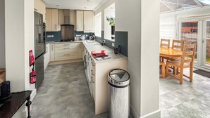 Una cocina moderna con una isla central, electrodomésticos integrados y un comedor con mesa y sillas.