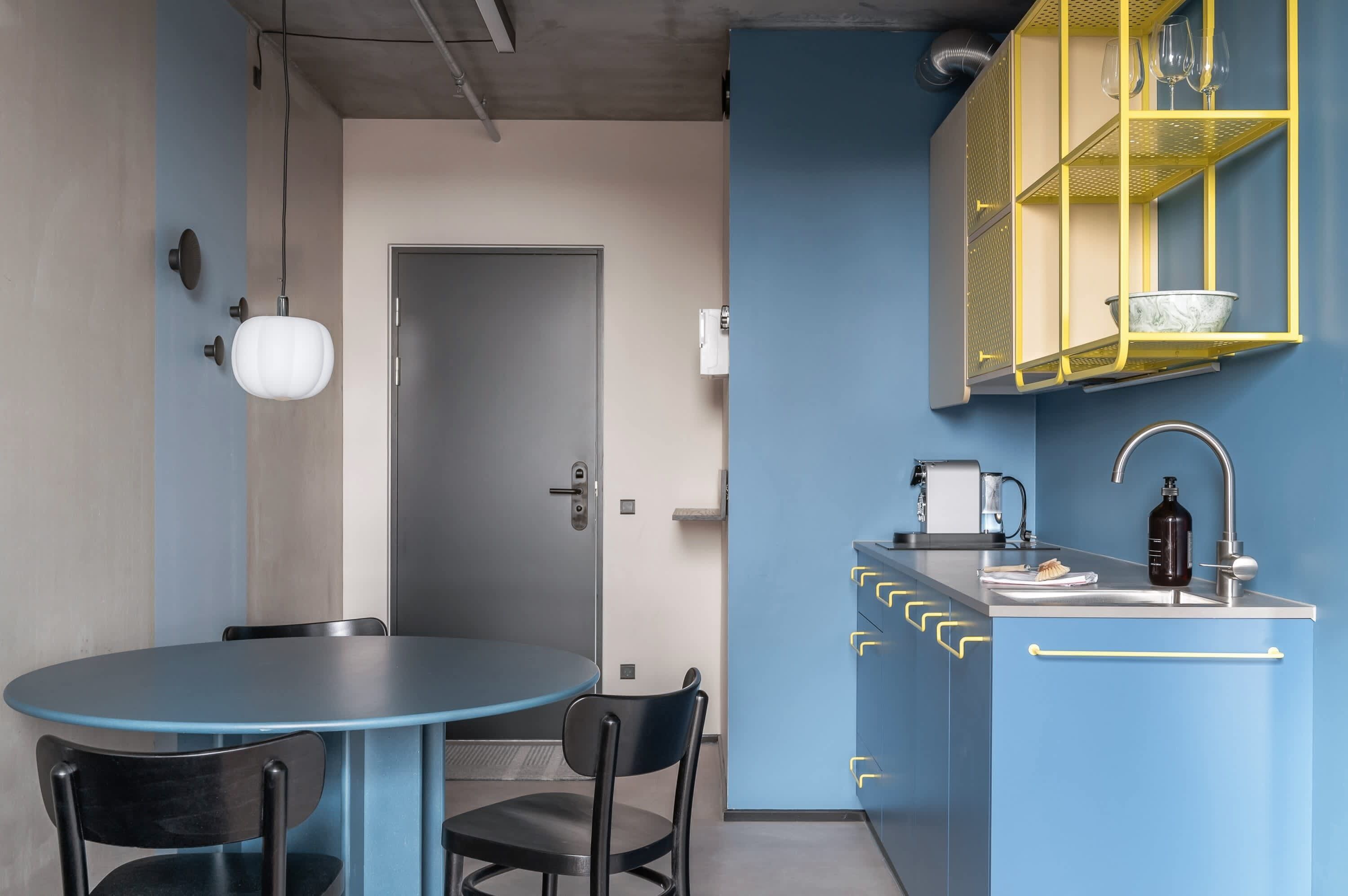 Une cuisine de taille réduite avec un meuble bleu, un évier et un petit plan de travail.