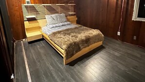 A wooden-paneled bedroom with a bed, nightstands, and a window.