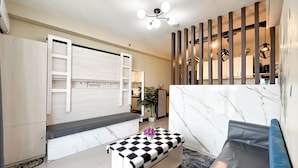 Una sala de estar moderna con sofá, banqueta, escalera de madera y una pared decorativa con un cartel que dice 'Family'.