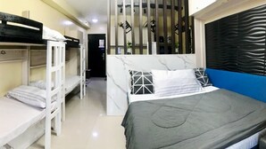 Habitación de hotel compacta con literas, una mesita de noche pequeña y una planta en maceta.