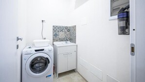A compact laundry room with a washing machine, a sink, and a cabinet. - Cozy seaside villa a few meters from the beach for couples and families (Tre Fontane)