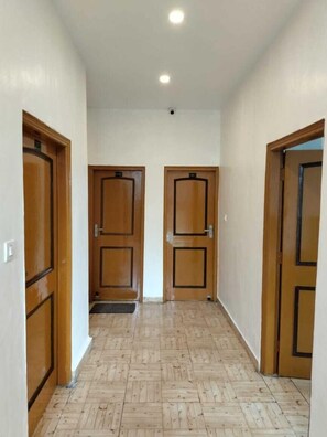 A hallway with wooden doors and a tiled floor. - The Galley (Dharamshala)