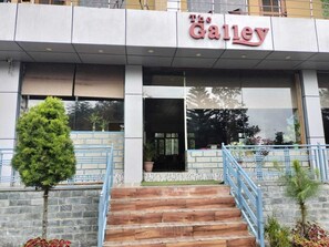 The exterior of The Gallery building with a staircase leading to the entrance, a small tree, and a railing. - The Galley (Dharamshala)