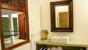 A bathroom with a white sink, a mirror, and a decorative vase.