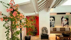 A spacious hallway with a modern design, featuring potted plants, a sofa, and artwork on the walls.