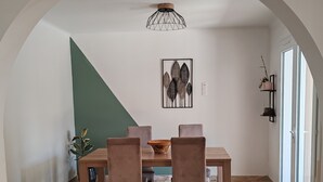 A dining area with a wooden table and chairs, a chandelier, a wall-mounted plant, and a painting. - Charming 3-bedroom house with WiFi, piscine, and AC in welcoming Saint-Raphaël (Saint-Raphaël)