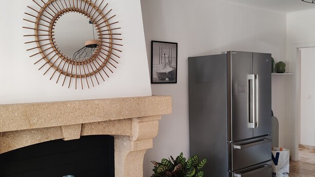 A modern kitchen with a built-in stone fireplace, a stainless steel refrigerator, and a decorative mirror. - Charming 3-bedroom house with WiFi, piscine, and AC in welcoming Saint-Raphaël (Saint-Raphaël)