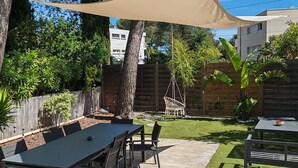 An outdoor patio with a table and chairs, surrounded by trees and a wooden fence. - Charming 3-bedroom house with WiFi, piscine, and AC in welcoming Saint-Raphaël (Saint-Raphaël)