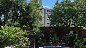 A swimming pool with a wooden deck, surrounded by trees and a building in the background. - Charming 3-bedroom house with WiFi, piscine, and AC in welcoming Saint-Raphaël (Saint-Raphaël)