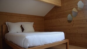A wooden-paneled room with a bed, wooden beams, and a wall-mounted mirror. - Family home in the heart of the Tarentaise (Moûtiers)